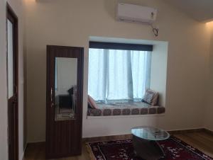 a room with a window with a couch and a mirror at Maanjoofarms Pilani in Pilani