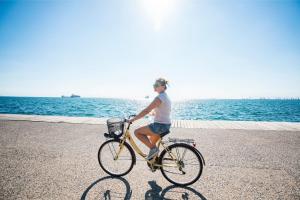 a woman riding a bike next to the water at Camping Saint-Gildas-de-Rhuys in Saint-Gildas-de-Rhuys