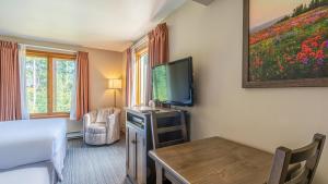 a room with a bed and a television and a table at Cahilty #265 in Sun Peaks