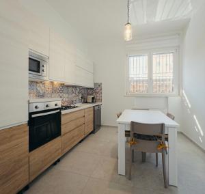 a kitchen with white cabinets and a table and a stove at Giosalea Tropea in Tropea