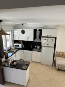 a kitchen with white cabinets and a white refrigerator at Eos in Çeşme
