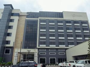 a large building with cars parked in front of it at Tripod By Pedestal Hotel in Owerri
