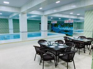 a dining room with tables and chairs and a swimming pool at Amina in Samarkand