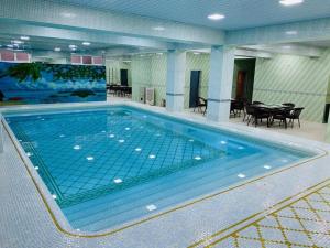 a large swimming pool in a room with tables and chairs at Amina in Samarkand +6 photos