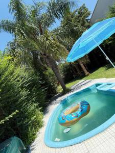 a pool with an umbrella and a hot dog in it at Casaquinta zona Aeropuerto Sauce Viejo in Santa Fe