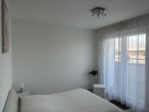 a white bedroom with a bed and a window at Appartement de standing, parking privé, climatisé, proche du centre-ville et la gare centre in Avignon