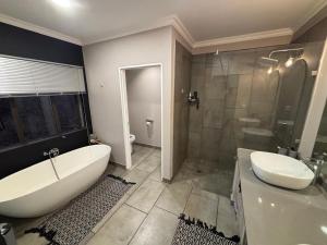 a bathroom with a tub and a toilet and a sink at House 110 in Hoedspruit