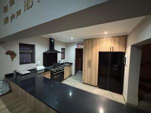 a kitchen with a black refrigerator and wooden cabinets at House 110 in Hoedspruit