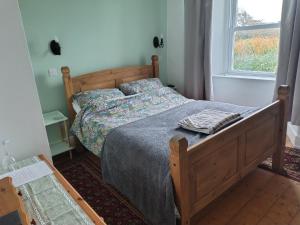 a bedroom with a bed with a blanket and a window at Sharlands Farm Bed and Breakfast in Bude