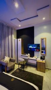 a living room with a couch and a tv at Flora By Bibaley Hotel in Kaduna