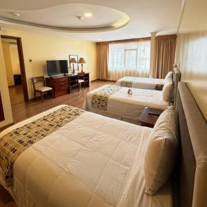 ein Hotelzimmer mit zwei Betten und einem Fernseher in der Unterkunft Hotel Republica in Quito