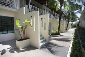 a white building with stairs and plants and palm trees at Impress Resort, Phuket - Free scheduled shuttle from Hotel to Phuket Airport in Thalang