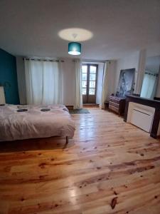 a bedroom with a bed and a wooden floor at Apparemment spacieux in Massat