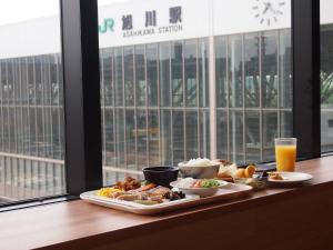 旭川旭川JR酒店的桌子上有两盘食物和一杯橙汁