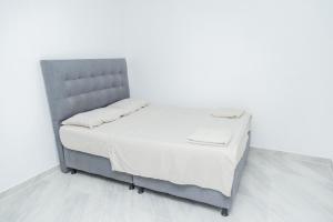 a bed with a gray headboard in a white room at Apartamentos King Arthur in Punta Seca