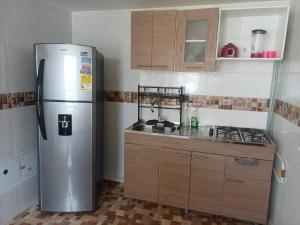 a kitchen with a stainless steel refrigerator and wooden cabinets at Apartamento Aboleda Campestre in Ibagué