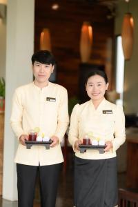two people standing next to each other holding plates of food at Luang Prabang View Hotel in Luang Prabang