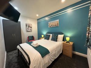 a bedroom with a large bed with a blue wall at Minstead Houses - 5 Bedroom Contractor House Sleeps 9 Parking for 2 Vans Near Bromford Duddeston Fort Dunlop Star City HS2 in Birmingham