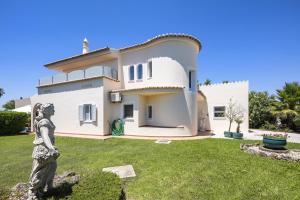 a large white house with a statue in the yard at Casa Juniper in Praia do Carvoeiro