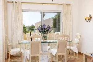 a dining room with a table with chairs and a vase of flowers at Casa Juniper in Praia do Carvoeiro