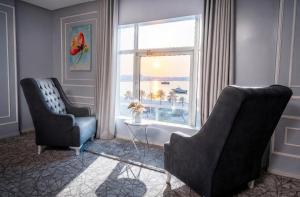 a living room with two chairs and a window at Golden Garden Al Corniche in Dammam