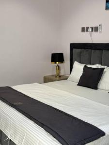 a bed with a black and white blanket and a lamp at Flora By Bibaley Hotel in Kaduna +7 photos