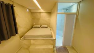 a small room with a bed and a glass door at Pousada Jabuticabeira in Jaguaruna