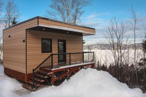 a small cabin with a deck in the snow at Refuge du Fjord in Saguenay