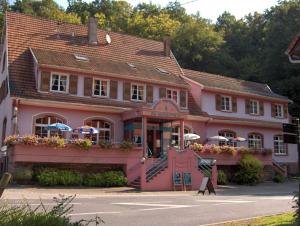 un bâtiment rose avec des parasols devant lui dans l'établissement Hotel-Restaurant du Windstein, à Windstein