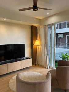 a living room with a flat screen tv and two chairs at Aerovista Suites - Neon Homeotel- 1 kms from Airport in Pune