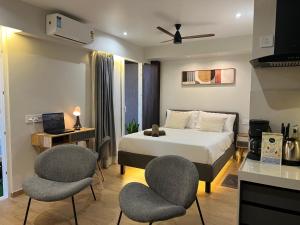 a hotel room with a bed and two chairs at Aerovista Suites - Neon Homeotel- 1 kms from Airport in Pune