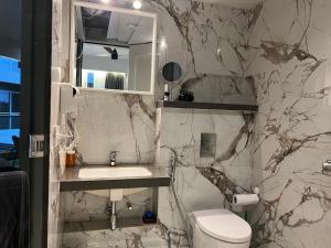 a bathroom with a toilet and a sink and a mirror at Aerovista Suites - Neon Homeotel- 1 kms from Airport in Pune +36 photos