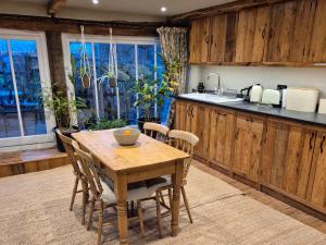 a kitchen with a wooden table with chairs and a counter at The Old Mill Annexe in Jacobstowe