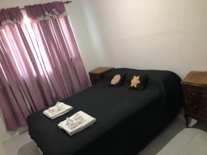 a bedroom with a black bed with towels on it at Espacio Marea in Puerto Madryn
