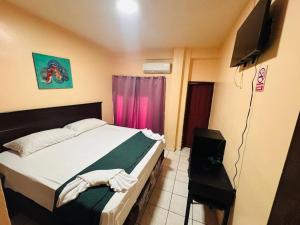 a bedroom with a bed and a flat screen tv at Hotel Palace in San Pedro Sula