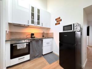 a kitchen with a black refrigerator and white cabinets at Le Chenin 2 Pers Proche gare Avon in Avon +7 photos