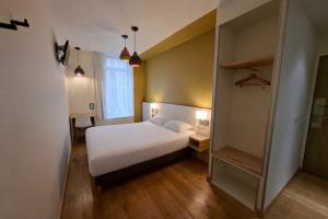 a small bedroom with a white bed and a desk at HOTEL AMBASSADEUR in Lille