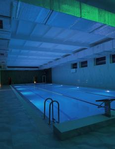 a large swimming pool with blue lights in a building at Галичанка Еліт SPA in Gornyak
