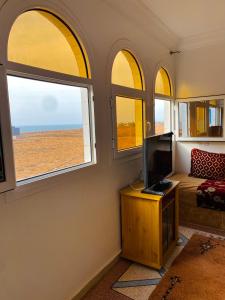 a room with a bed and a tv and windows at Ahmed mirleft in Sidi Ifni