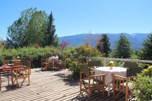 a deck with tables and chairs with mountains in the background at Habitación en Casa de Campo La Alborada in El Bolsón