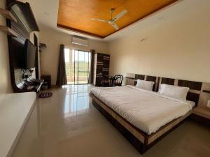 a bedroom with a bed and a flat screen tv at Gugal Bliss in Mahabaleshwar