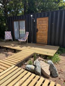 a wooden deck with a chair and a door at Nomade Balmaceda in Balmaceda