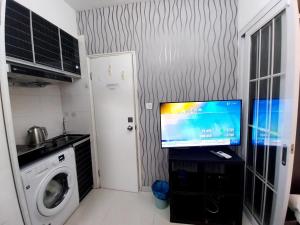 a small kitchen with a tv on a counter with a washing machine at bnb's in Hong Kong