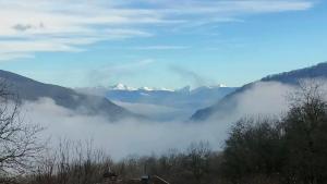 a misty valley with mountains in the distance with snow at L'Horizon - Maison en Pierres, Vue Alpes et Nature in La Burbanche