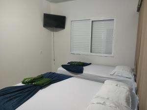 two beds in a white room with a window at Hotel Stones in Jaraguá