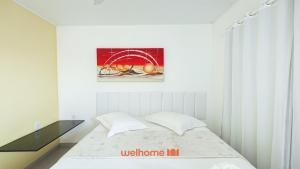 a white bedroom with a bed and a picture on the wall at Suite em Guriri Norte com Piscina e Academia in São Mateus