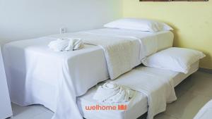 two beds in a room with white sheets and towels at Suite em Guriri Norte com Piscina e Academia in São Mateus +20 photos