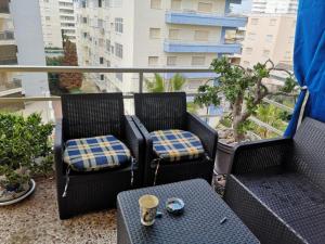 a balcony with two chairs and a table with a coffee cup at Sea views-Balcony-Sleeps 6-Parking-AirCon Heating in Daimuz
