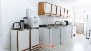 a kitchen with white cabinets and a counter top at Suite em Guriri Norte com Piscina e Academia in São Mateus