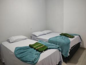 two beds with towels on them in a room at Hotel Stones in Jaraguá